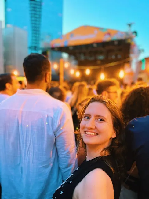 Foule de festival en soirée devant une scène, femme souriante au premier plan