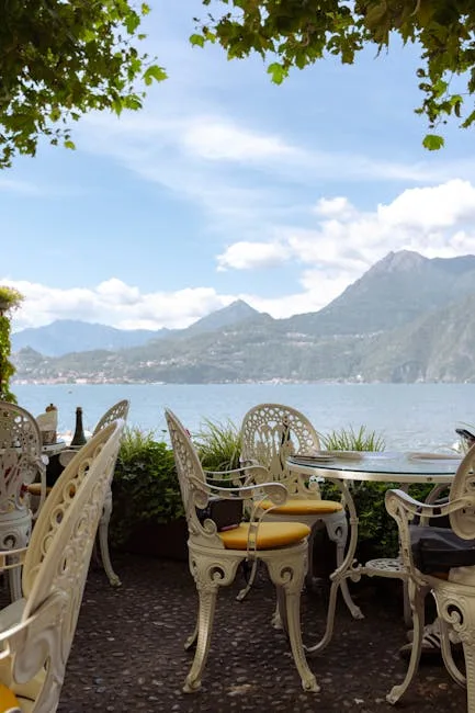 Ornate white cafe chairs with yellow cushions facing Lake Como mountains