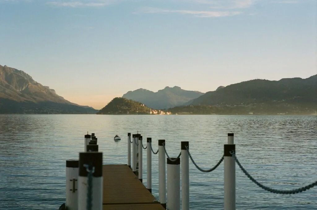 Steg mit Pfosten und Kette am Comer See, Insel sichtbar