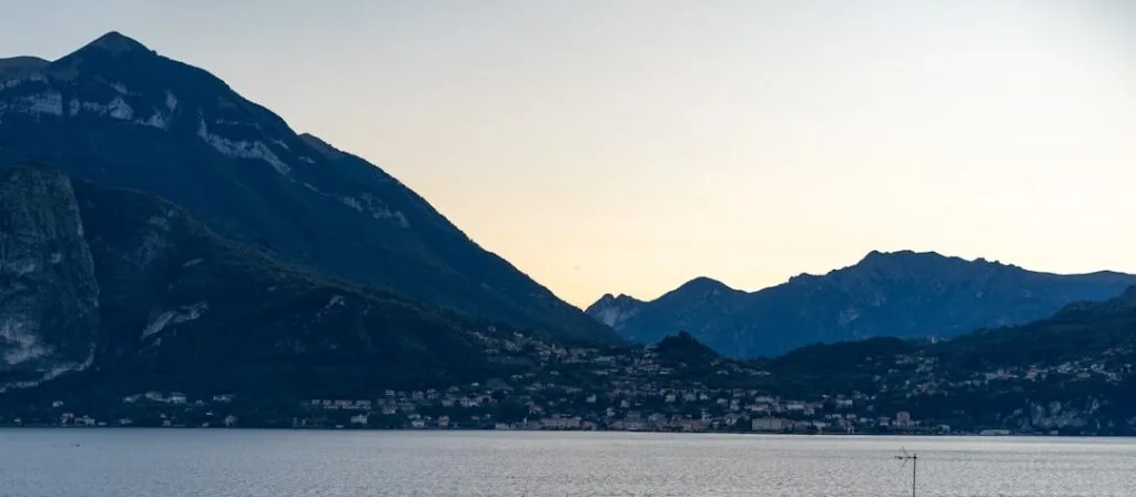 Dämmernde Bergsilhouette und Uferort am Comer See mit ruhigem Wasser