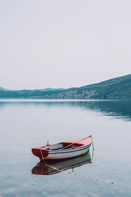 Rotes Ruderboot treibt ruhig auf dem Lac come, spiegelndes Wasser