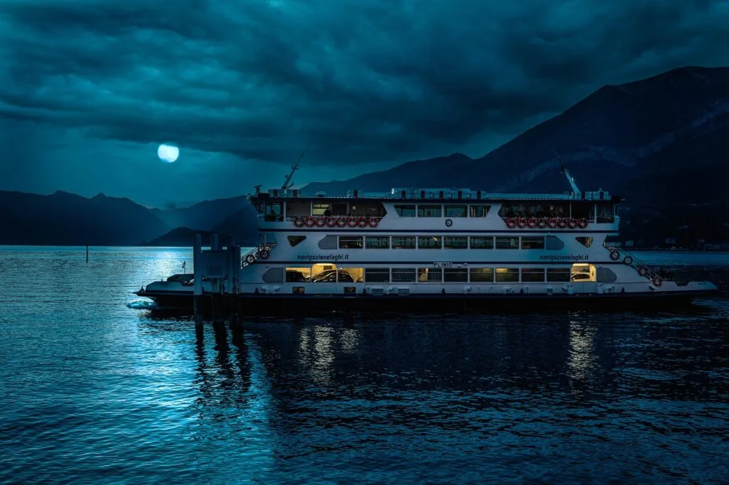 Fährschiff bei Mondlicht am Comer See, ruhige Wasserreflexionen