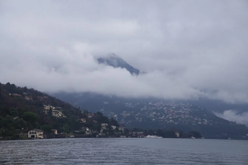 Nebel über dem Lac come, Uferhäuser und bergverhangene Landschaft