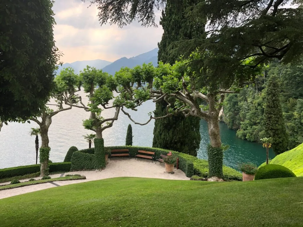 Bancs sous arbres taillés, pelouse et eau du Lac come