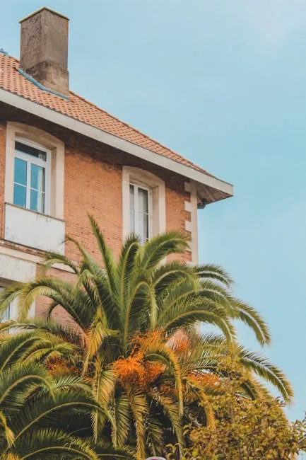 Backsteinhausfassade mit hoher Palme vor blauem Himmel in Menaggio