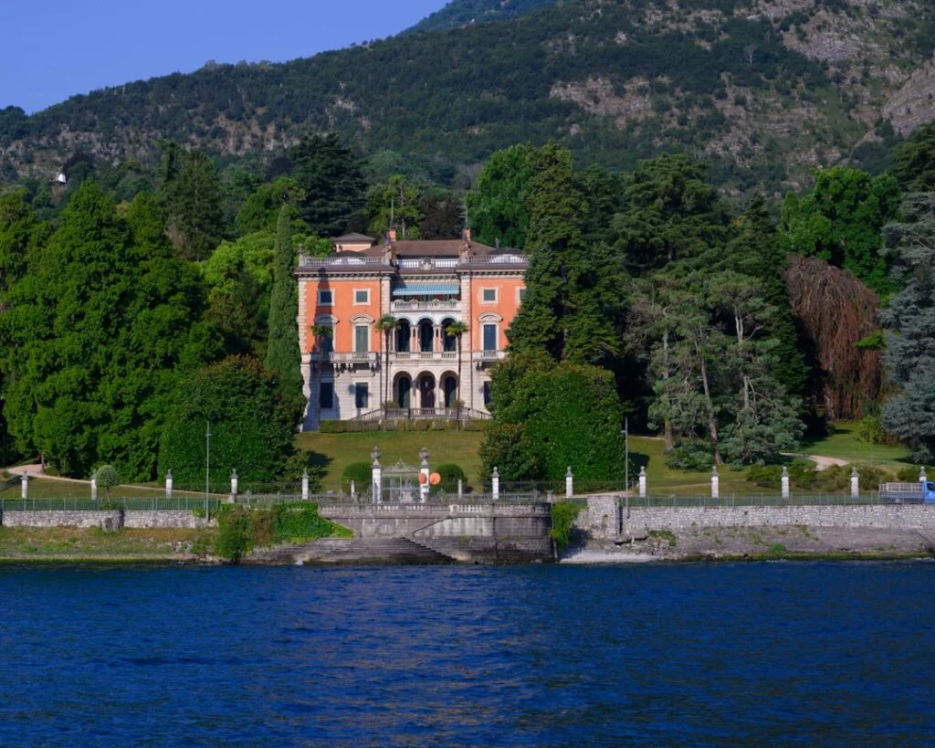 Villa orange bordée d'arbres, façade sur l'eau du Lac come