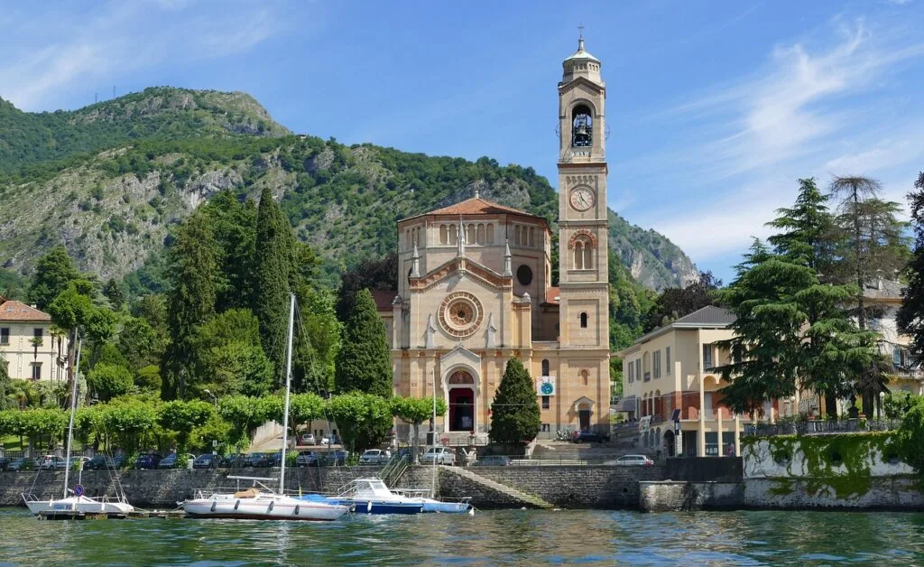 Kirche am Ufer des Comer Sees mit Booten und sichtbarem Glockenturm