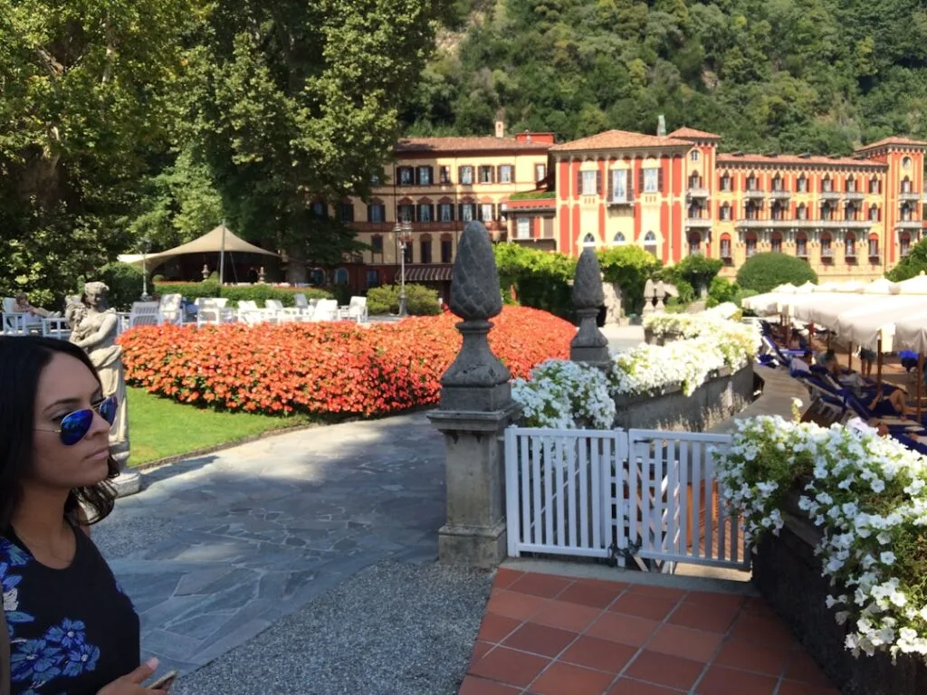 Garten mit roten Blumen und historischem Hotel am Comer See, Frau mit Sonnenbrille
