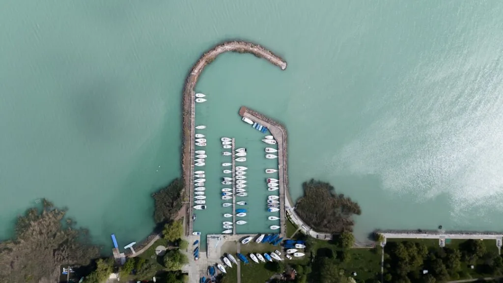 Luftaufnahme einer kleinen Marina mit türkisfarbenem Wasser am Comer See