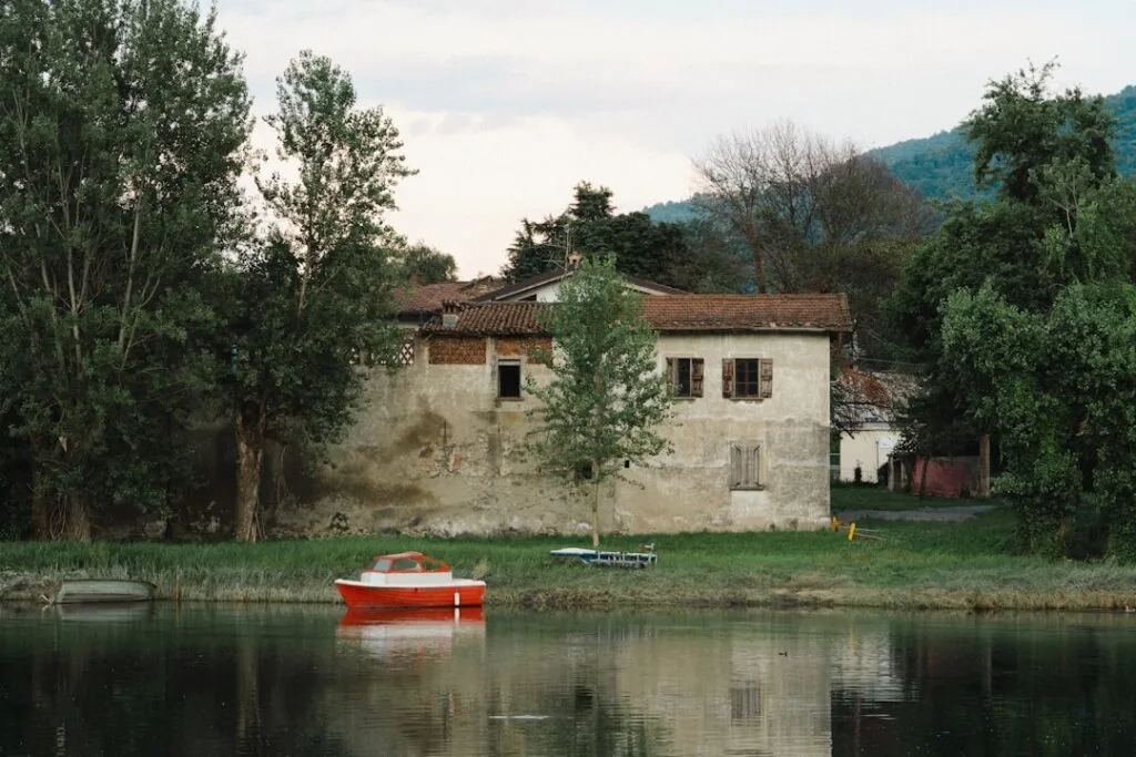 Rustikales Haus am Wasser mit kleinem roten Ruderboot auf dem Comer See