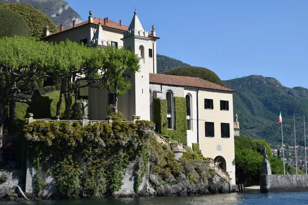 Pastellfarbene Villa auf Felsen am Comer See mit italienischer Flagge
