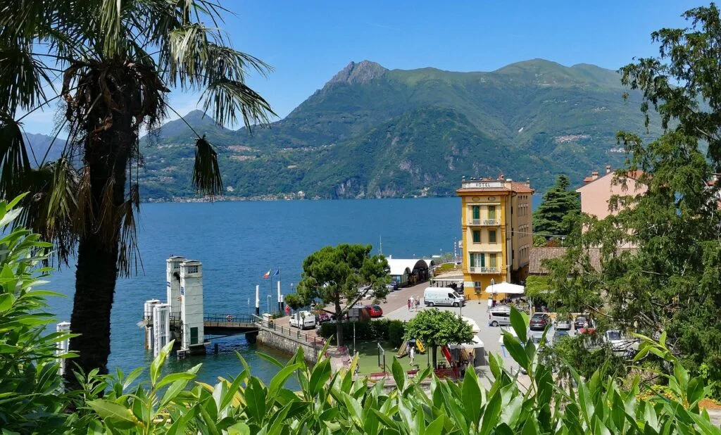 Palmenrahmen Blick auf Anlegestelle und gelbes Hotel am Lac come