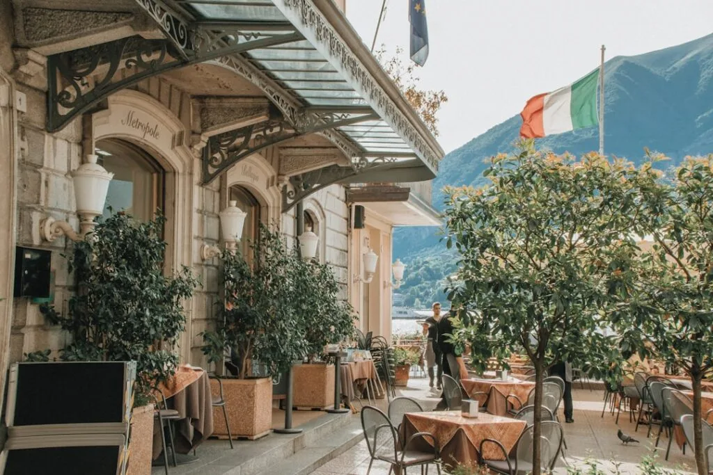 Lakeside café terrace with Italian flag overlooking Lake Como and mountains