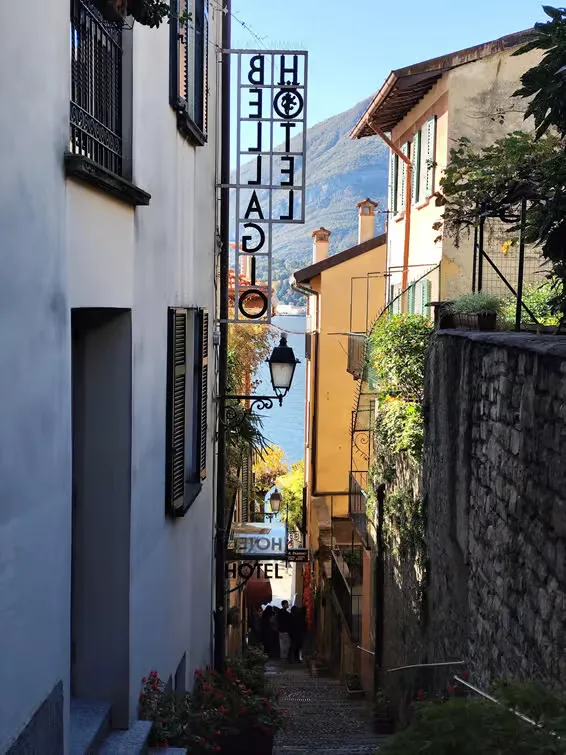 steile Gasse zum Lac come hinunter, Hotelschilder sichtbar.