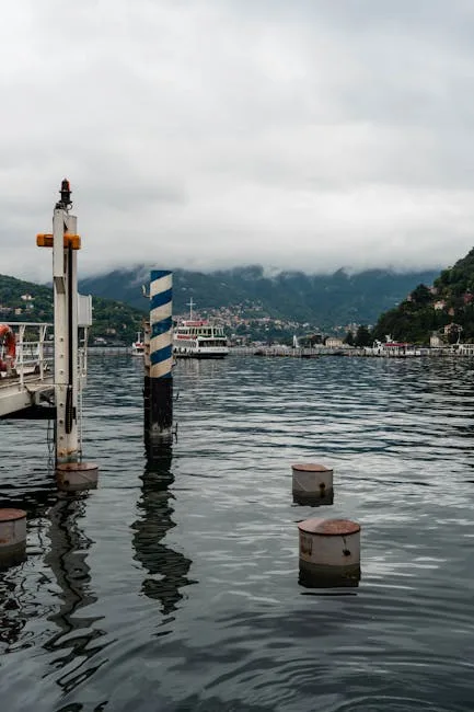 Striped mooring pole and distant ferry on Lake Como's calm water